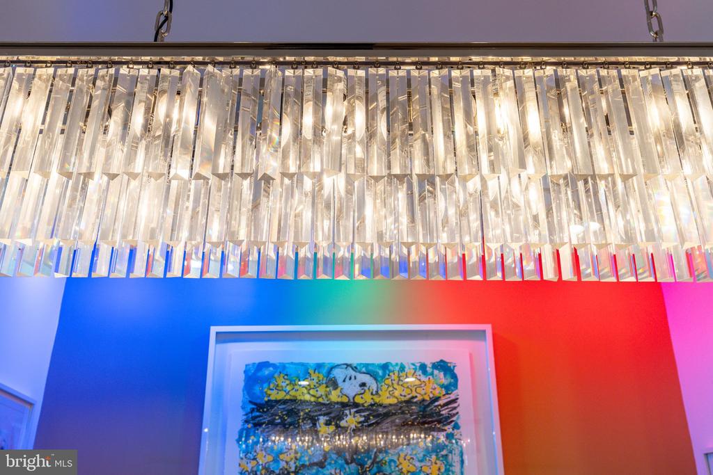 Crystal chandelier above framed abstract artwork on vivid blue and red walls.