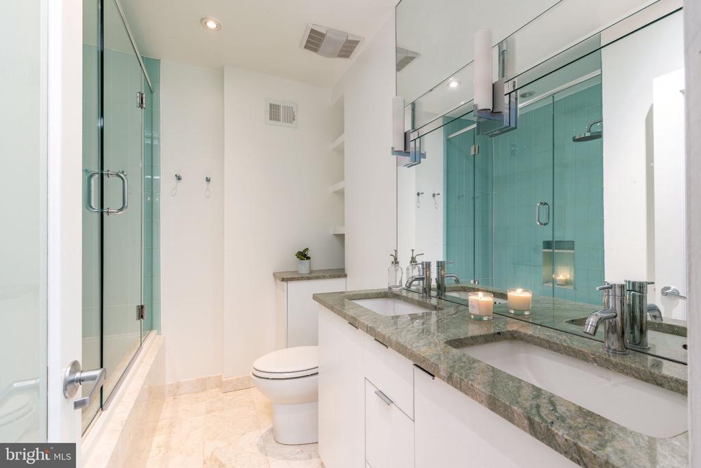 Bathroom with turquoise-tiled glass shower and a long granite double-sink vanity.