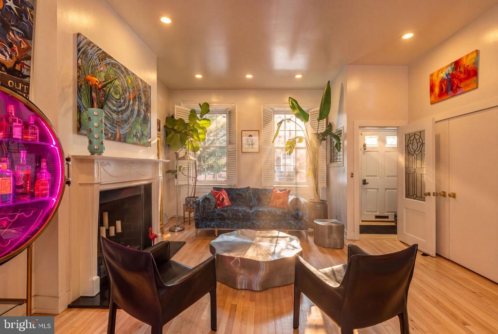 Living room with a white fireplace, blue sofa, leather chairs, and colorful artwork.