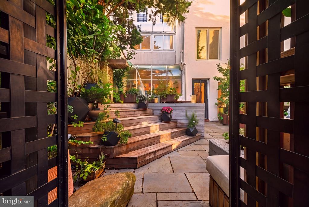 Landscaped courtyard with tiered wooden steps, potted plants, and a stone-paved patio.