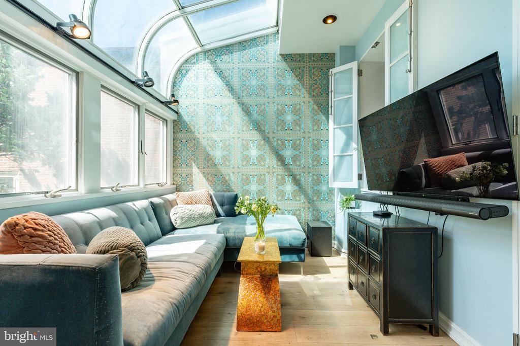 Living room with a curved glass ceiling, blue patterned tile wall, and sectional sofa.