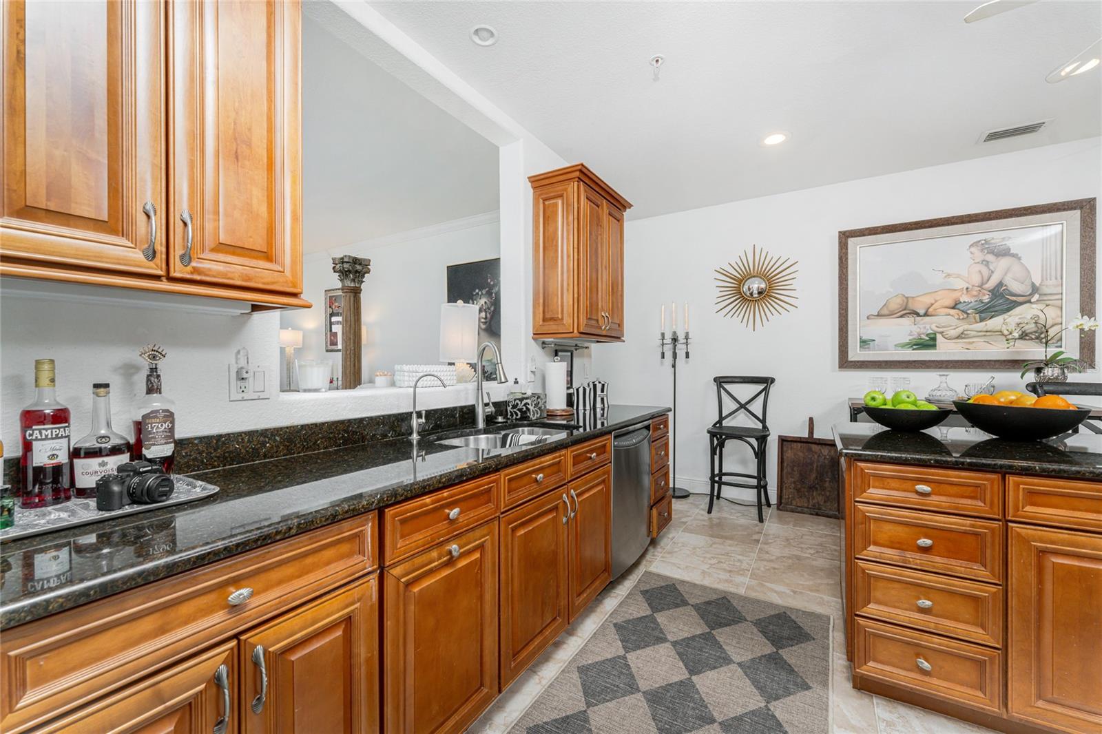 Kitchen with honey-colored wood cabinets, dark countertops, and a small dining area.