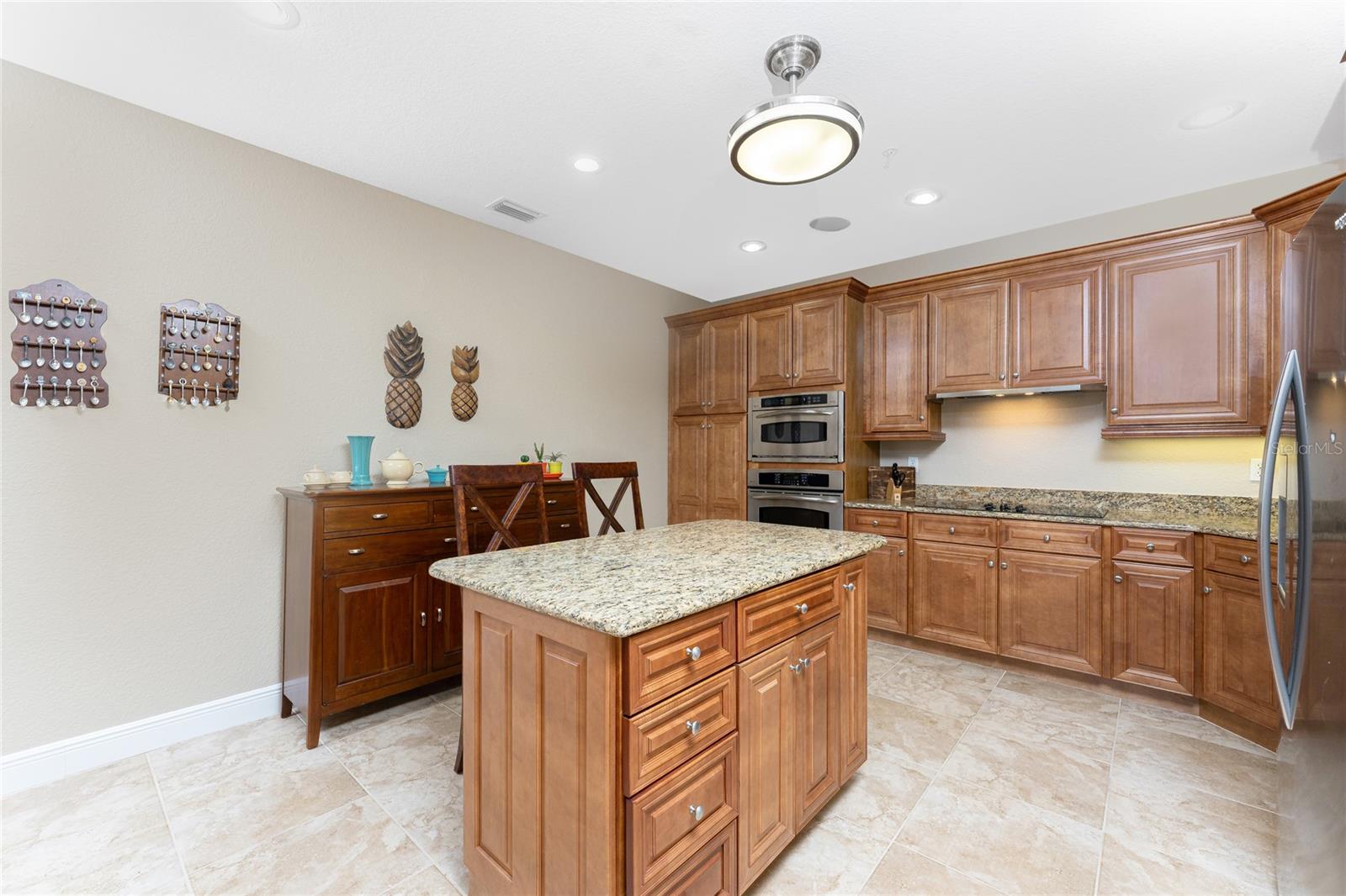 Kitchen with wood cabinets, granite island, and stainless steel appliances.
