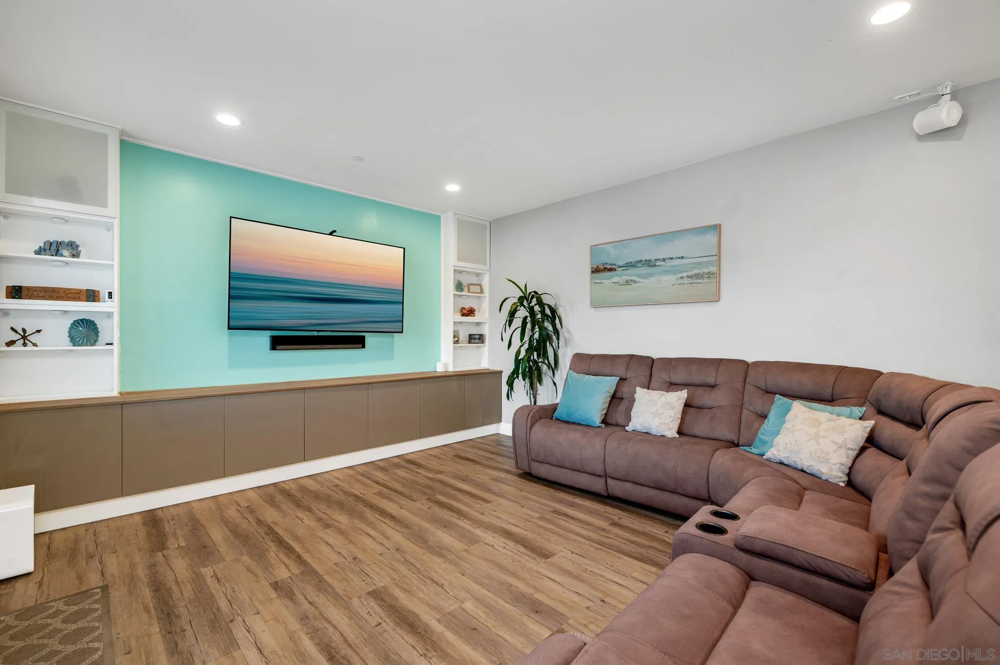 Living room with a brown sectional and a wall-mounted TV on a turquoise accent wall.
