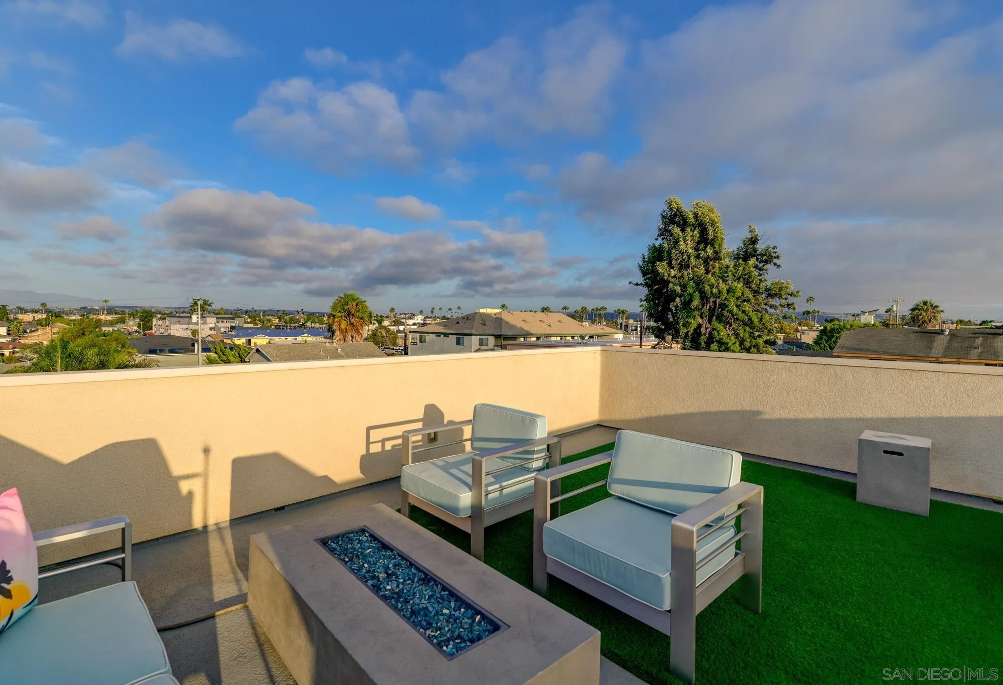 Rooftop patio with lounge chairs, a rectangular fire feature, and residential views.