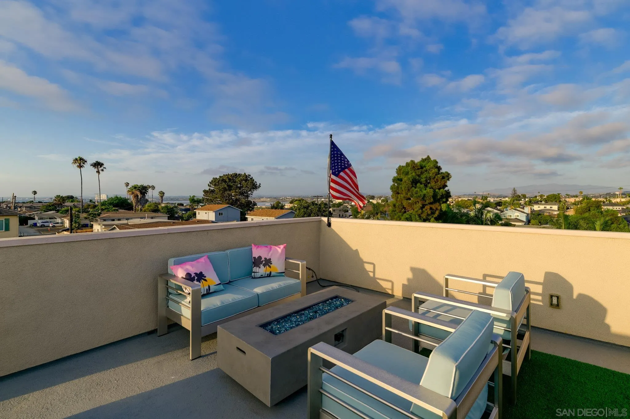 Rooftop terrace with blue seating and a fire pit overlooking the neighborhood.