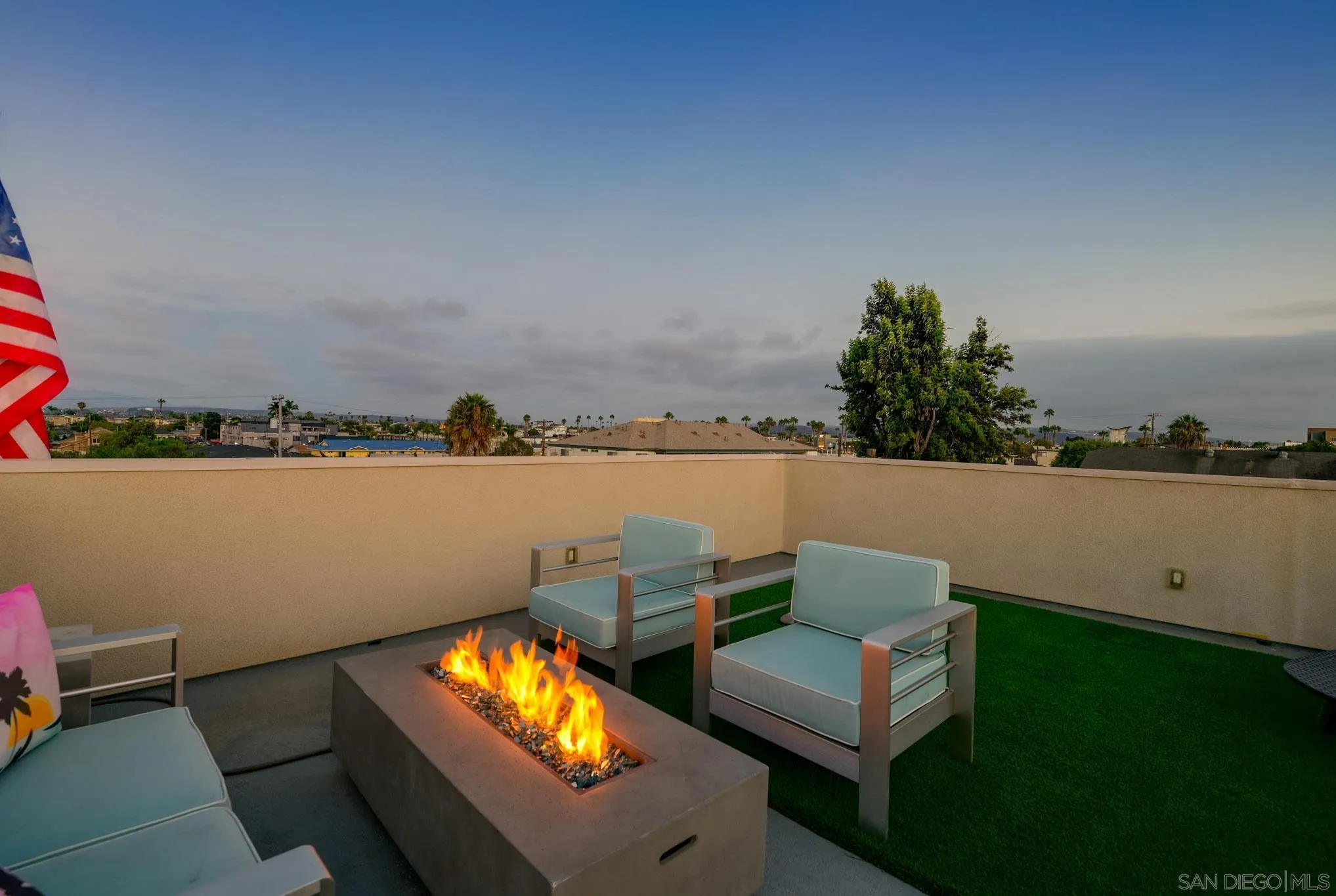 Rooftop patio with a lit fire pit, modern chairs, and neighborhood views.