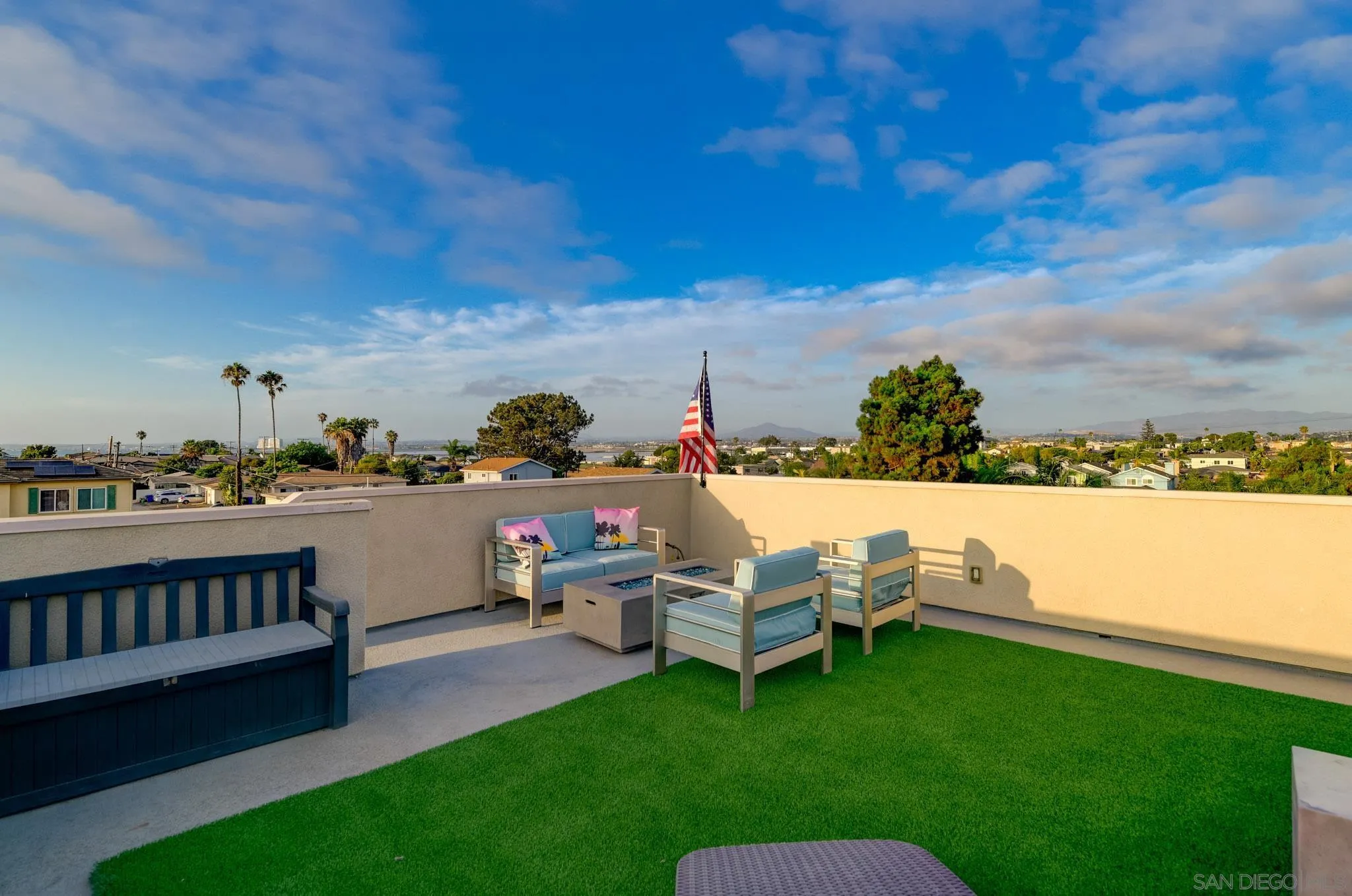 Rooftop patio with artificial grass, outdoor seating, a fire table, and neighborhood views.