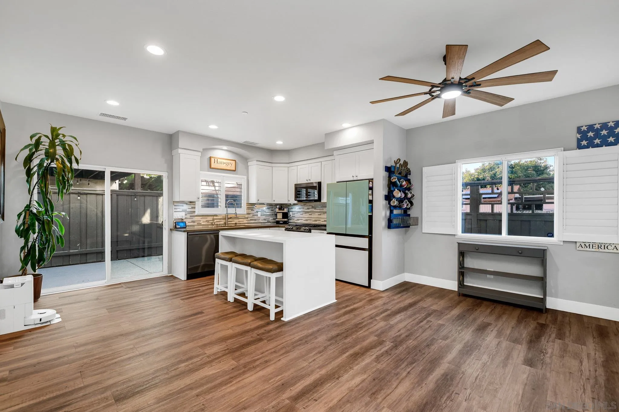 Open kitchen with white cabinetry, island seating, pale green refrigerator, and sliding glass doors.