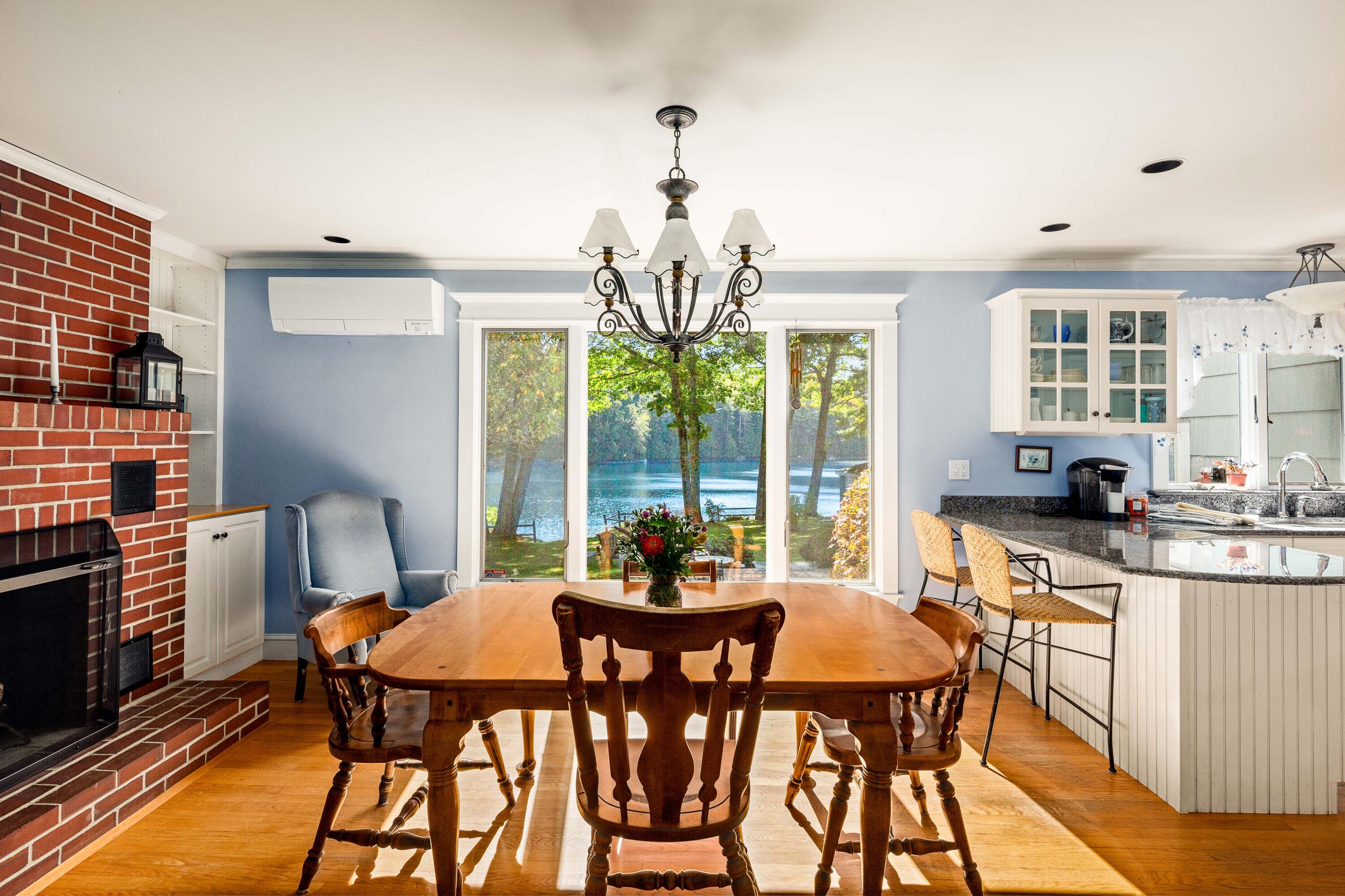 Dining area with a brick fireplace and lake views through large windows.