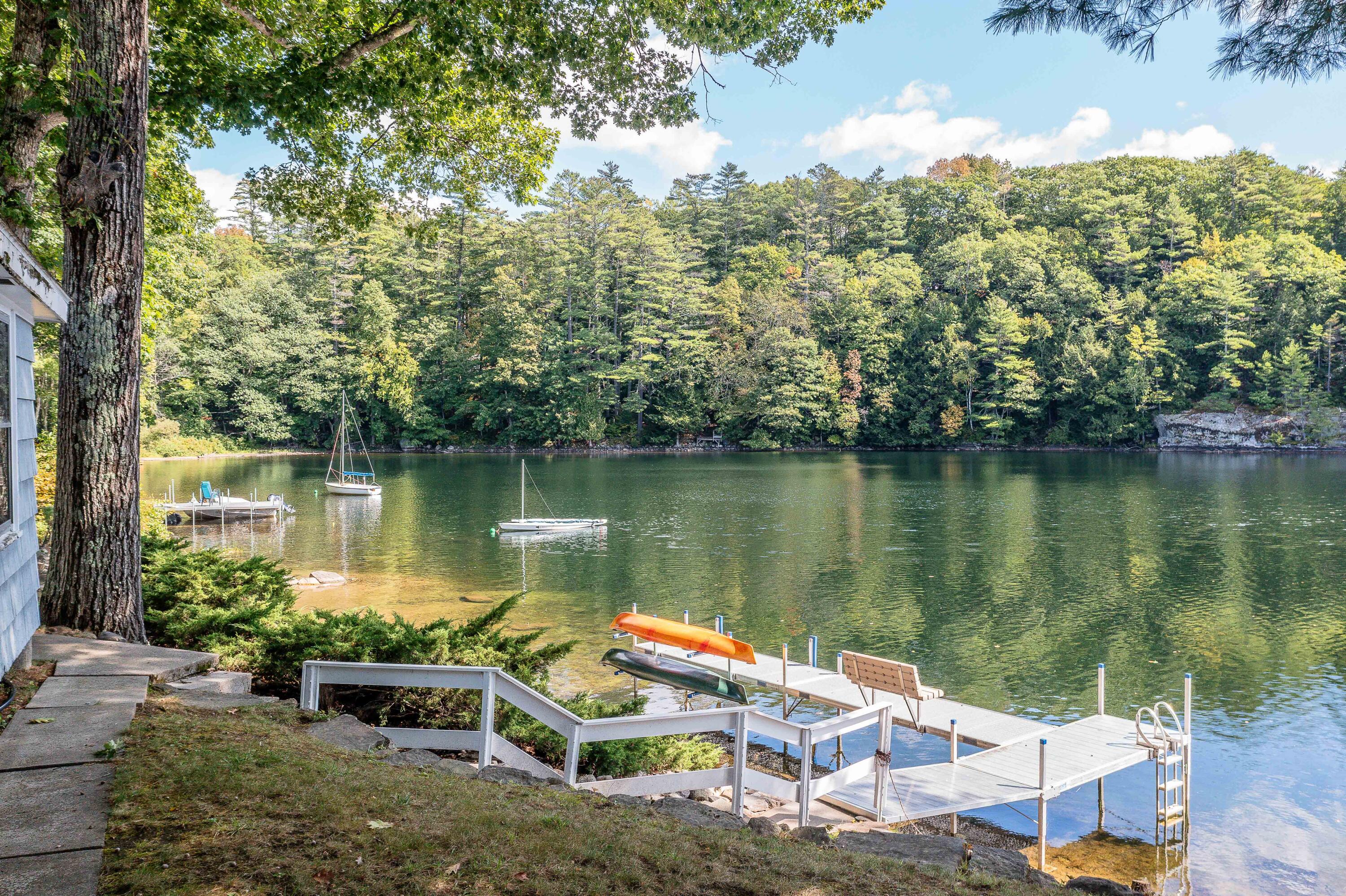 Waterfront dock with boats on a wooded lake beside the home.