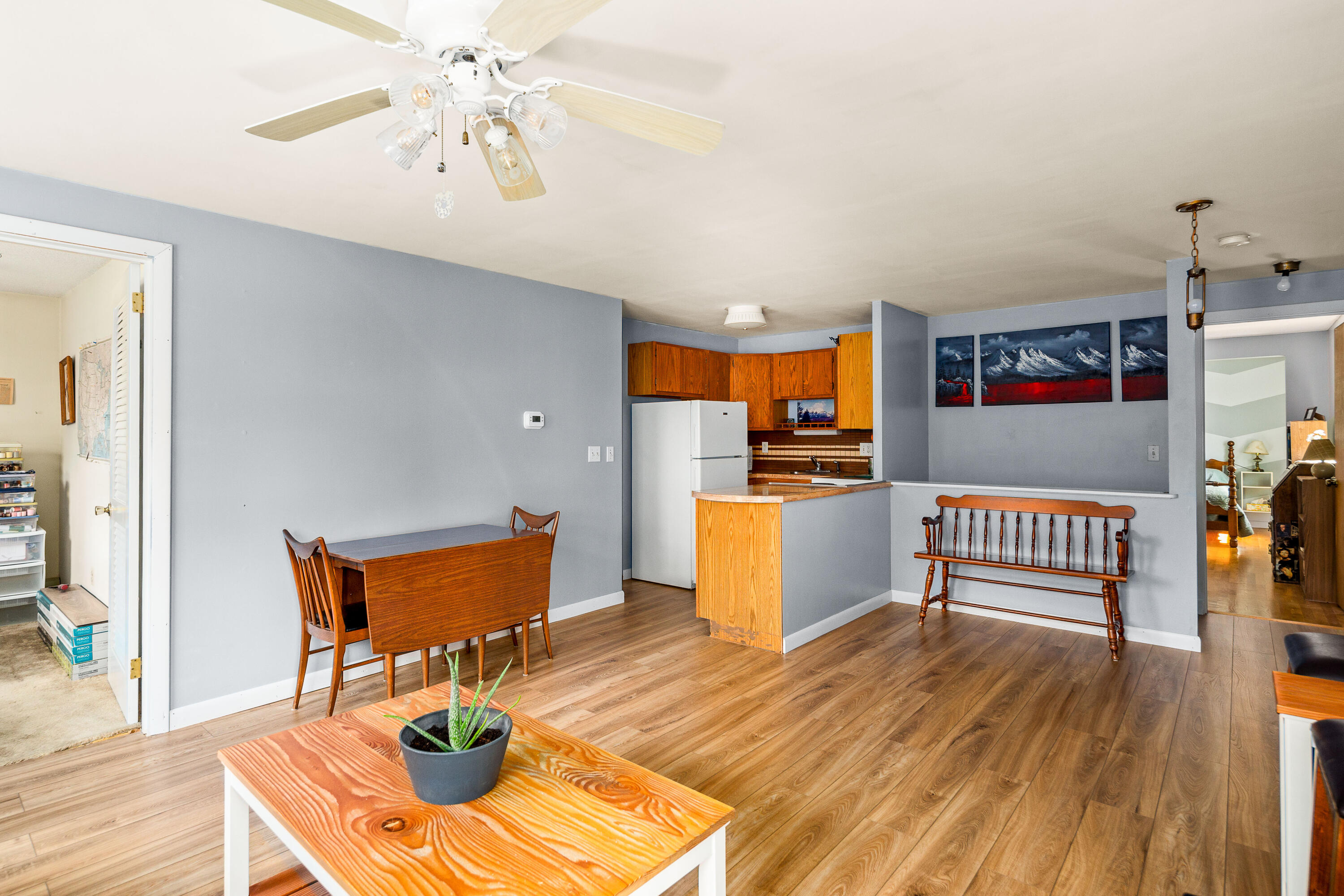 Open-plan dining area and kitchen with wood floors, gray walls, and a wooden breakfast counter.
