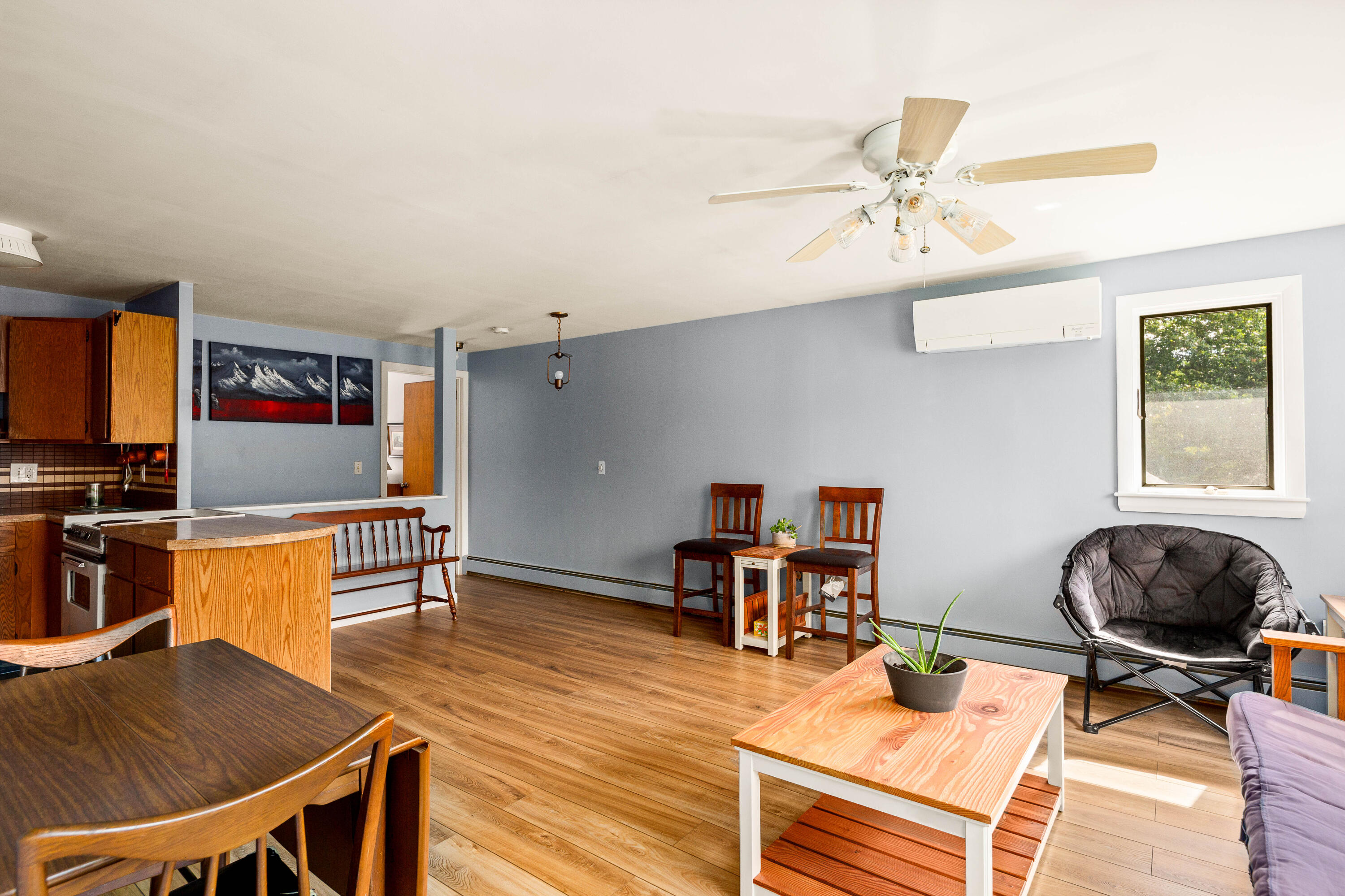 Open living and dining area with wood floors, a kitchen island, and ceiling fan.