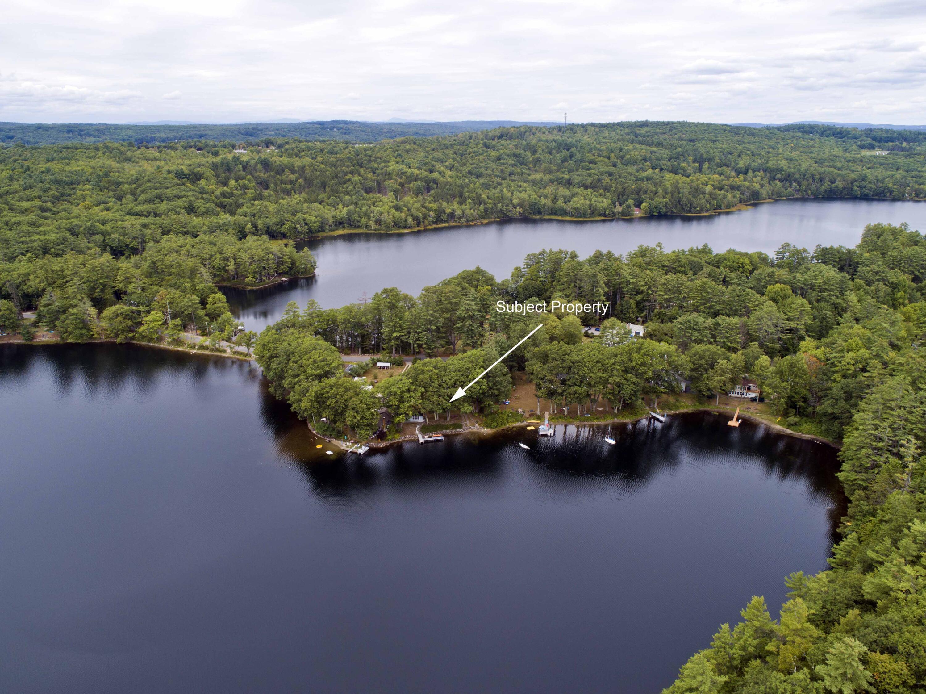 Aerial view of wooded lakefront property marked by an arrow.