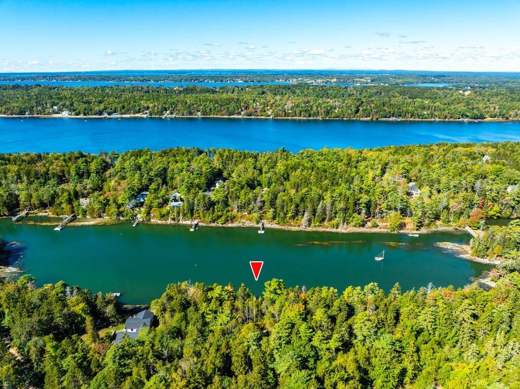 Aerial view of a wooded waterfront property marked beside a narrow inlet.
