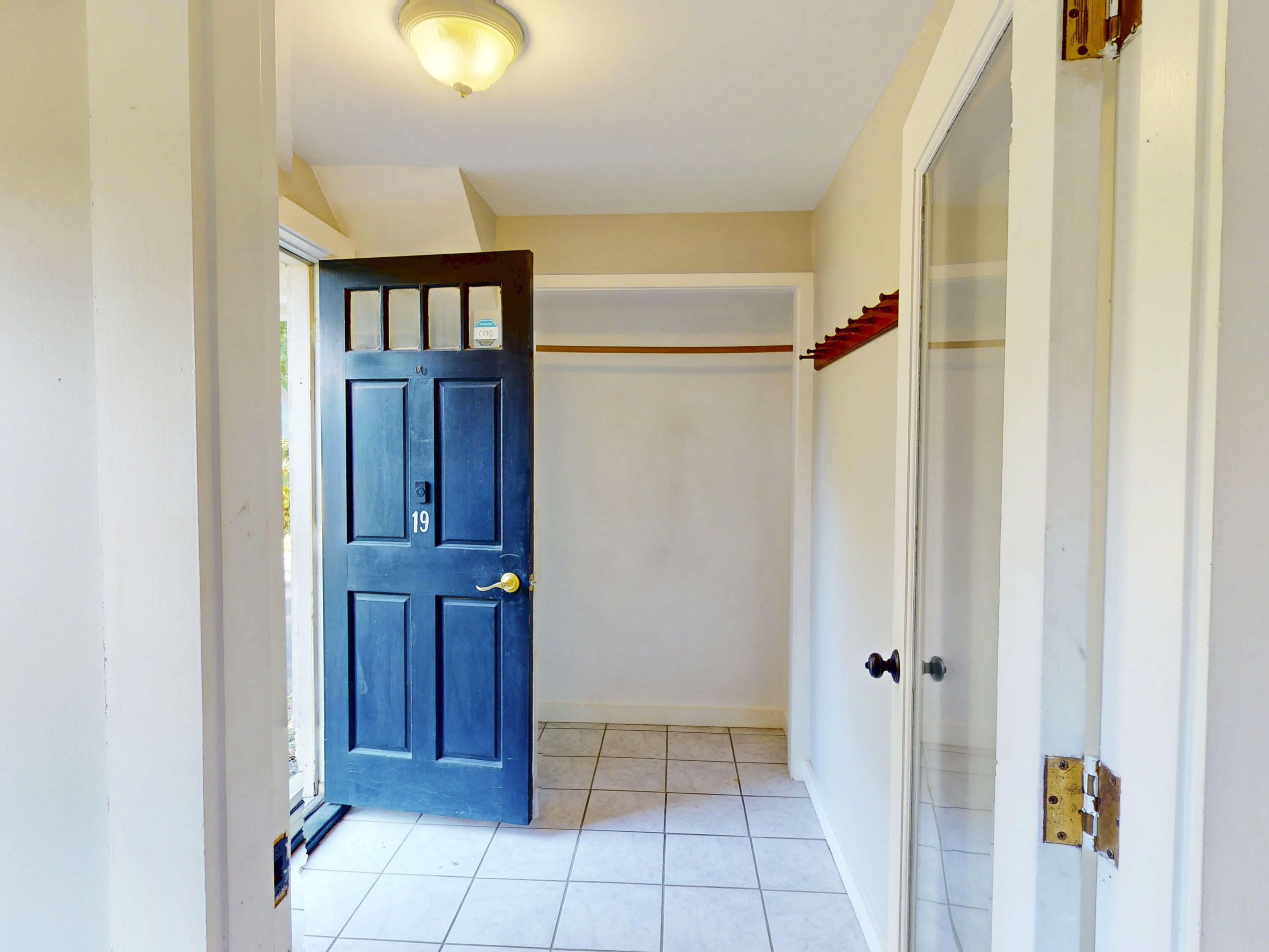 Entryway with a blue front door marked 19, tiled floor, and mirrored closet door.