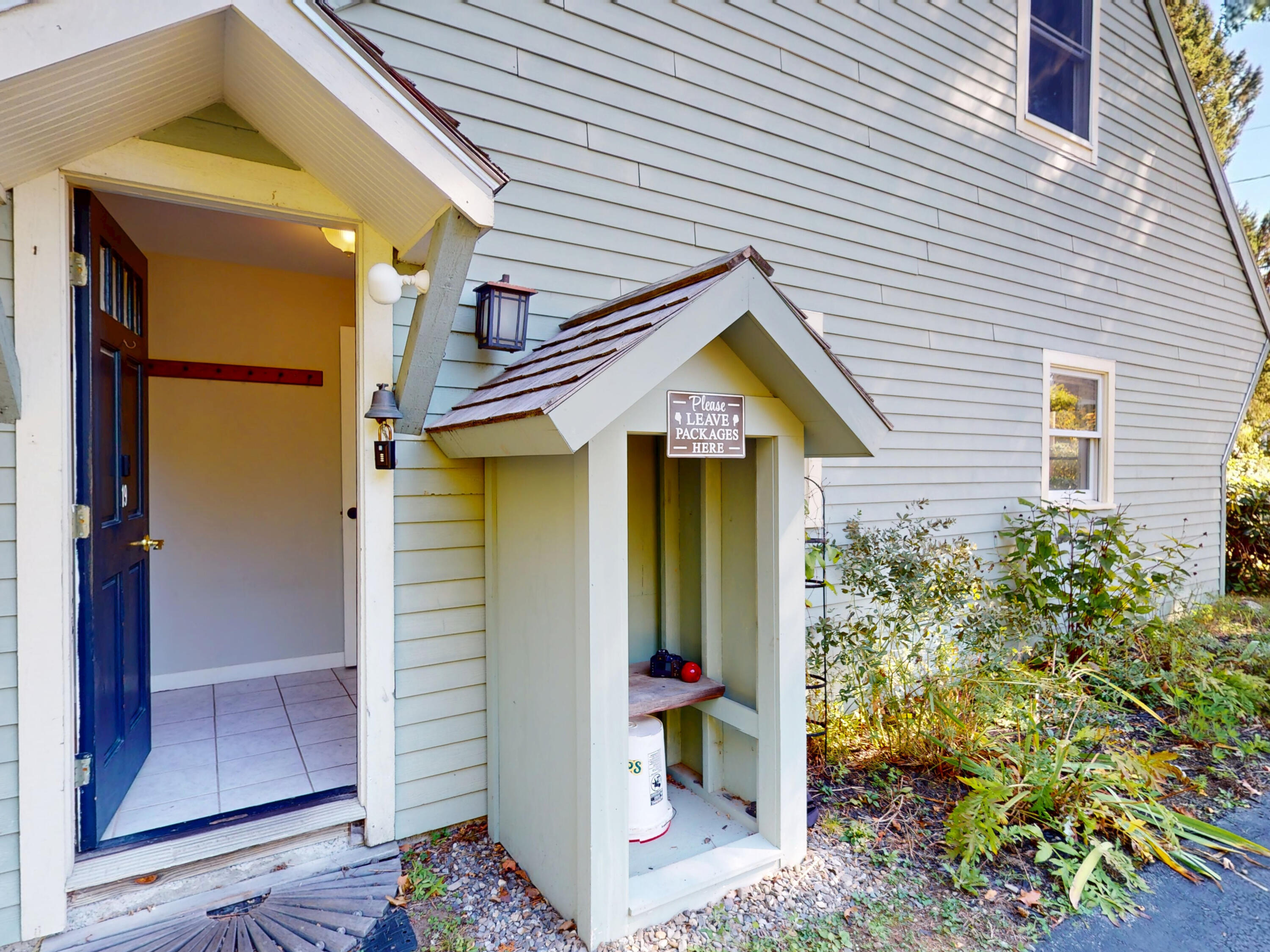 House entrance with an open navy door and a covered package drop-off nook.