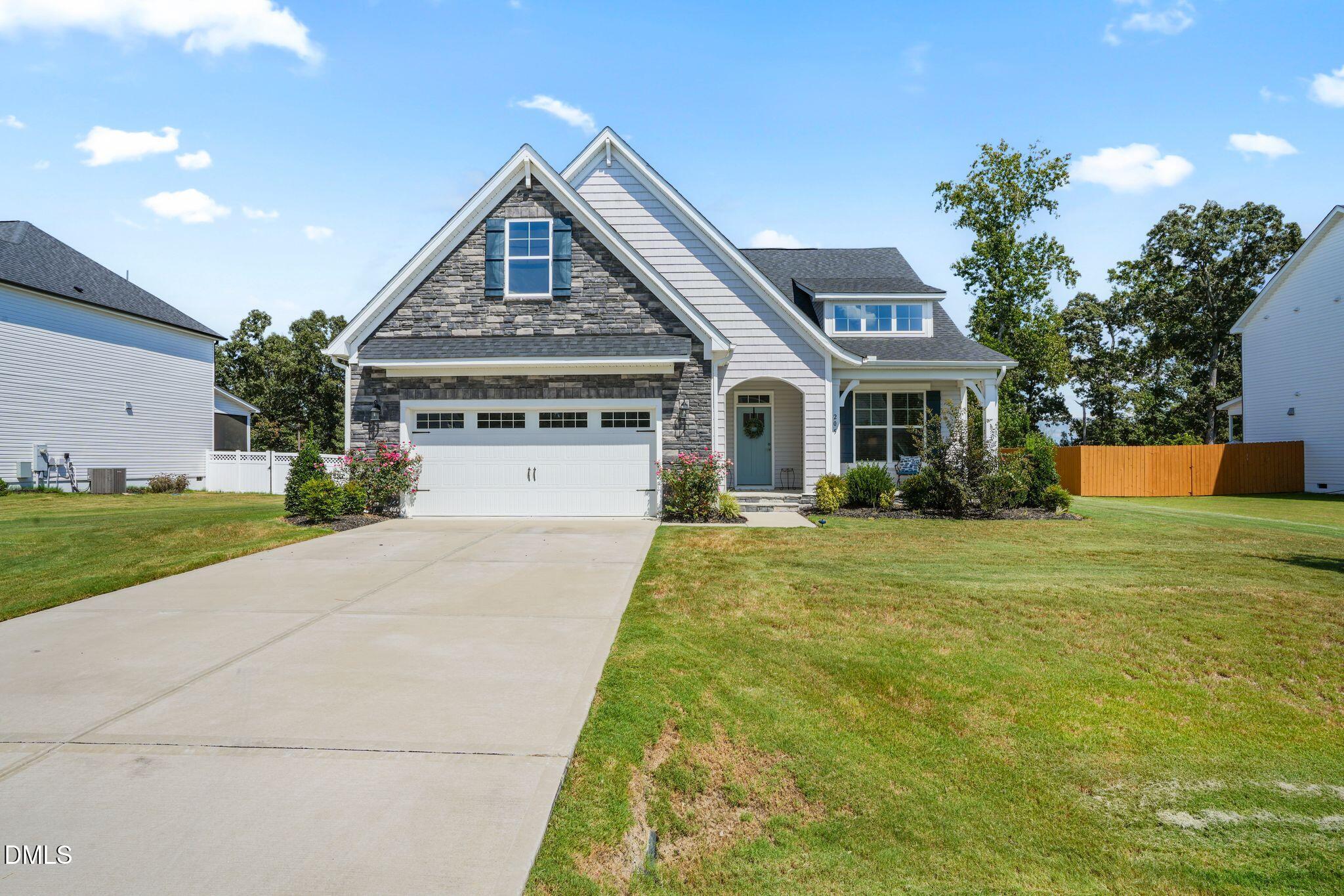 Two-story house with a stone-front gable, white garage door, and broad driveway.