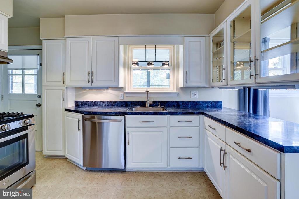 Kitchen with white cabinets, deep blue countertops, and a window above the sink.