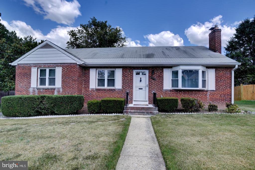 Single-story brick house with a bay window, chimney, and walkway to the front door.