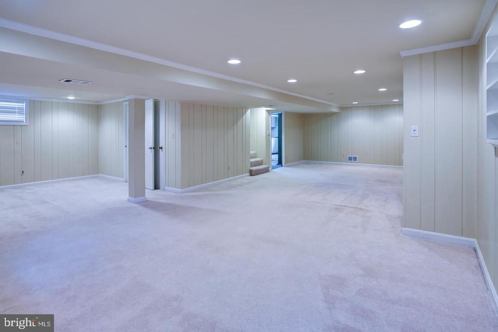 Finished basement with light carpet, paneled walls, and recessed lighting.