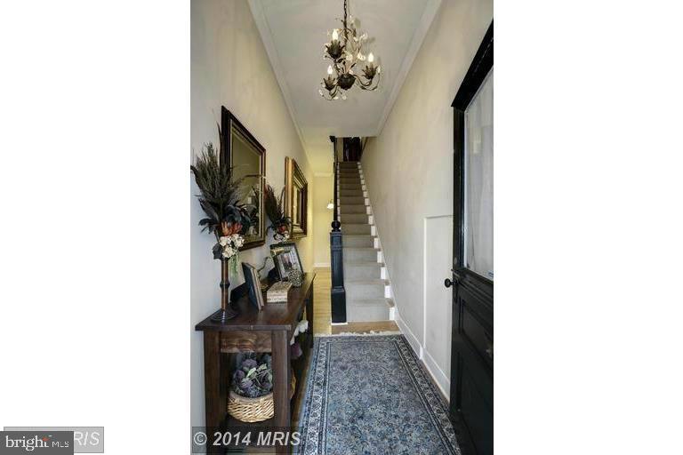 Entry hall with a patterned runner, dark wood console table, chandelier, and staircase.