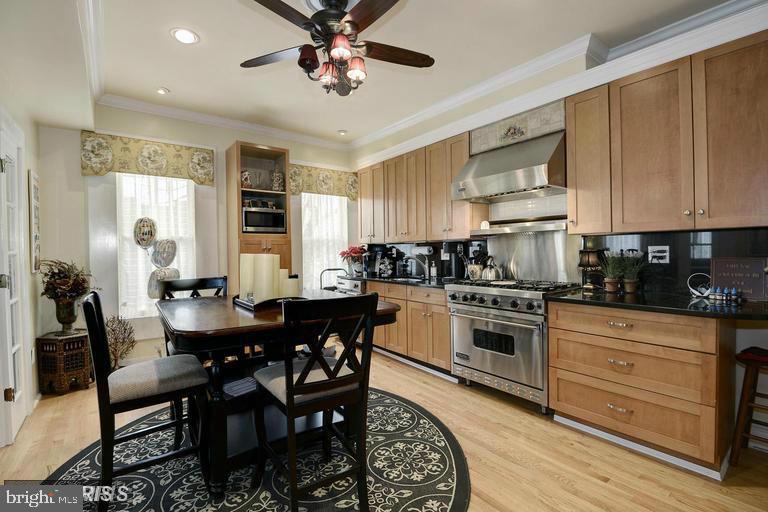 Kitchen with light wood cabinets, stainless steel appliances, and a dining table on a patterned rug.