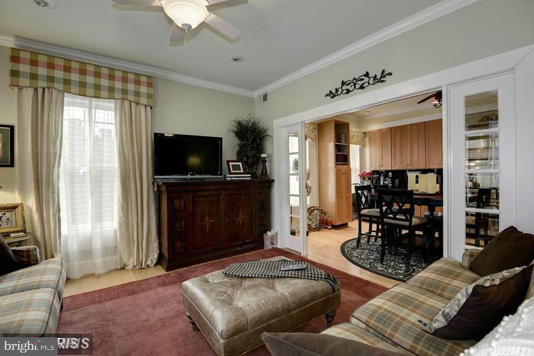 Living room with plaid sofas and leather ottoman, opening onto a dining area and kitchen.
