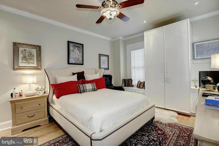 Bedroom with a white bed, red pillows, patterned rug, and tall white closets.