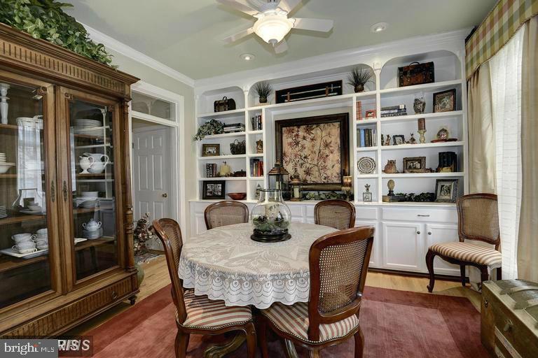 Dining room with a lace-covered table, wooden china cabinet, and white built-in display shelves.