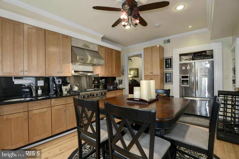 Kitchen and dining area with light wood cabinets, stainless steel appliances, and a large wooden table.