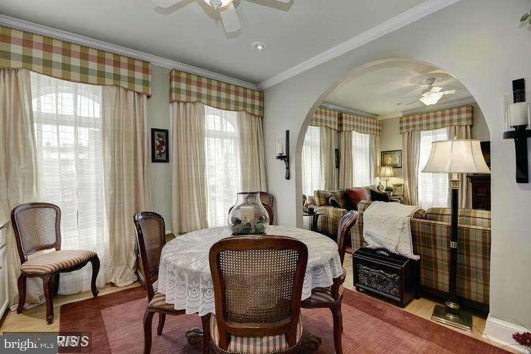 Dining room with a lace-covered table and cane-back chairs, opening to a plaid living room.
