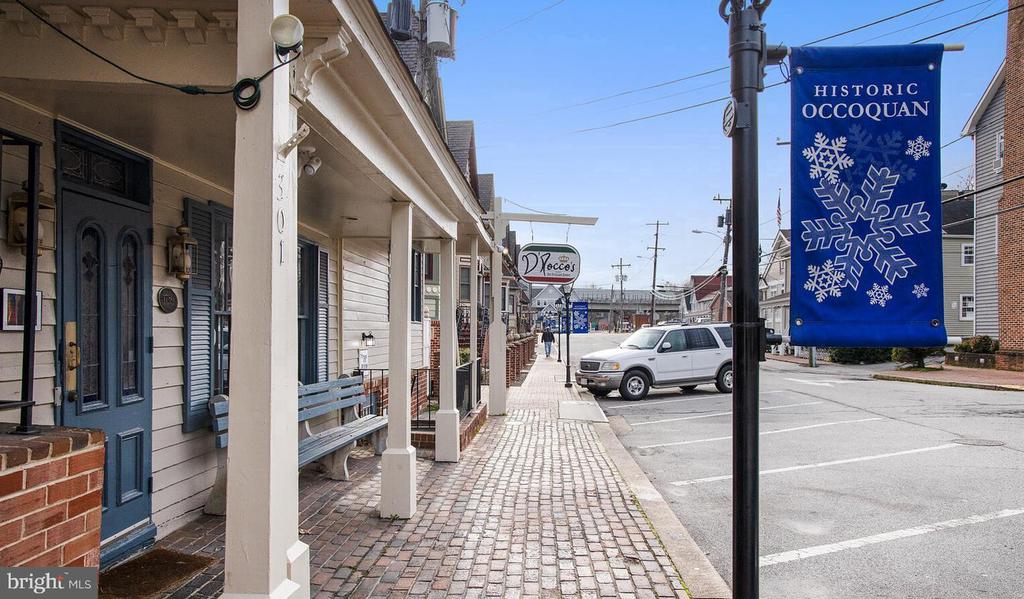 Historic Occoquan street with storefronts, brick sidewalks, and a blue snowflake banner.