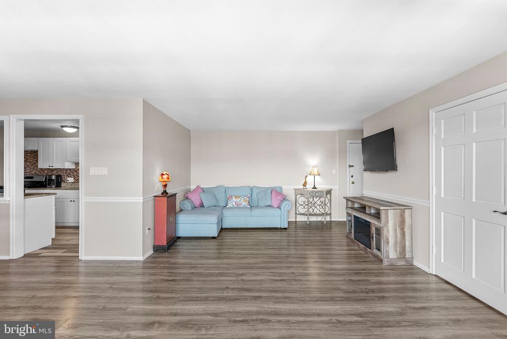 Living room with a light blue sectional, plank flooring, and wall-mounted television.
