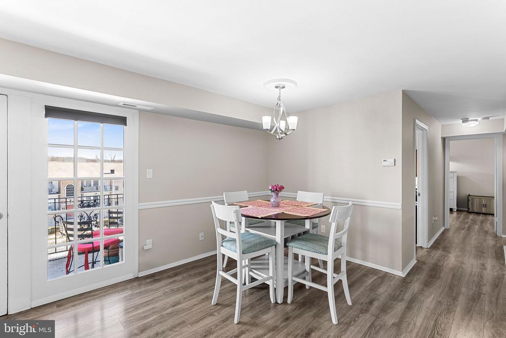 Dining area with a white table and chairs beside a glass-paned balcony door.