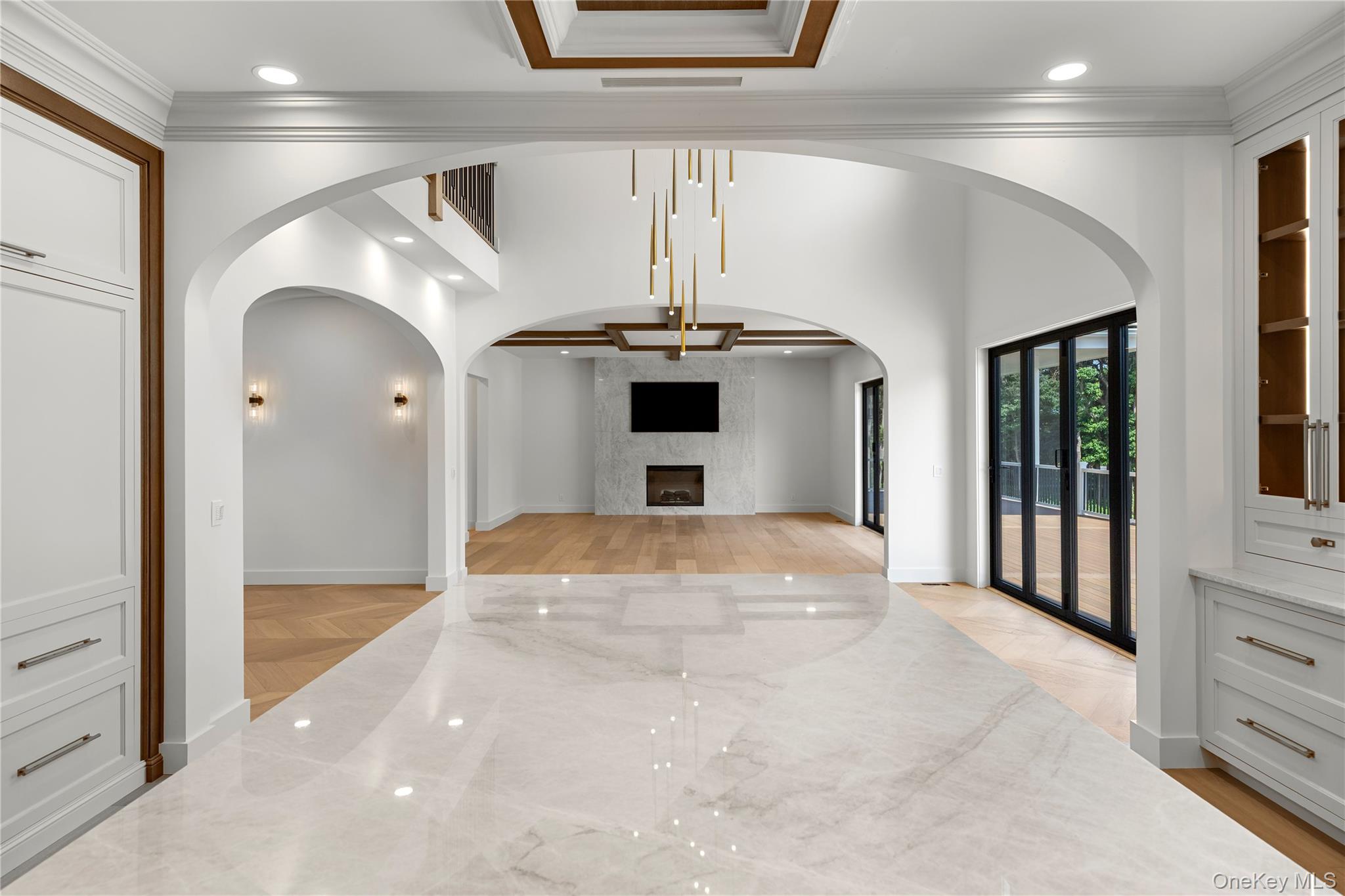 Unfurnished living room with arched openings, a marble fireplace wall, and sliding doors to a deck.