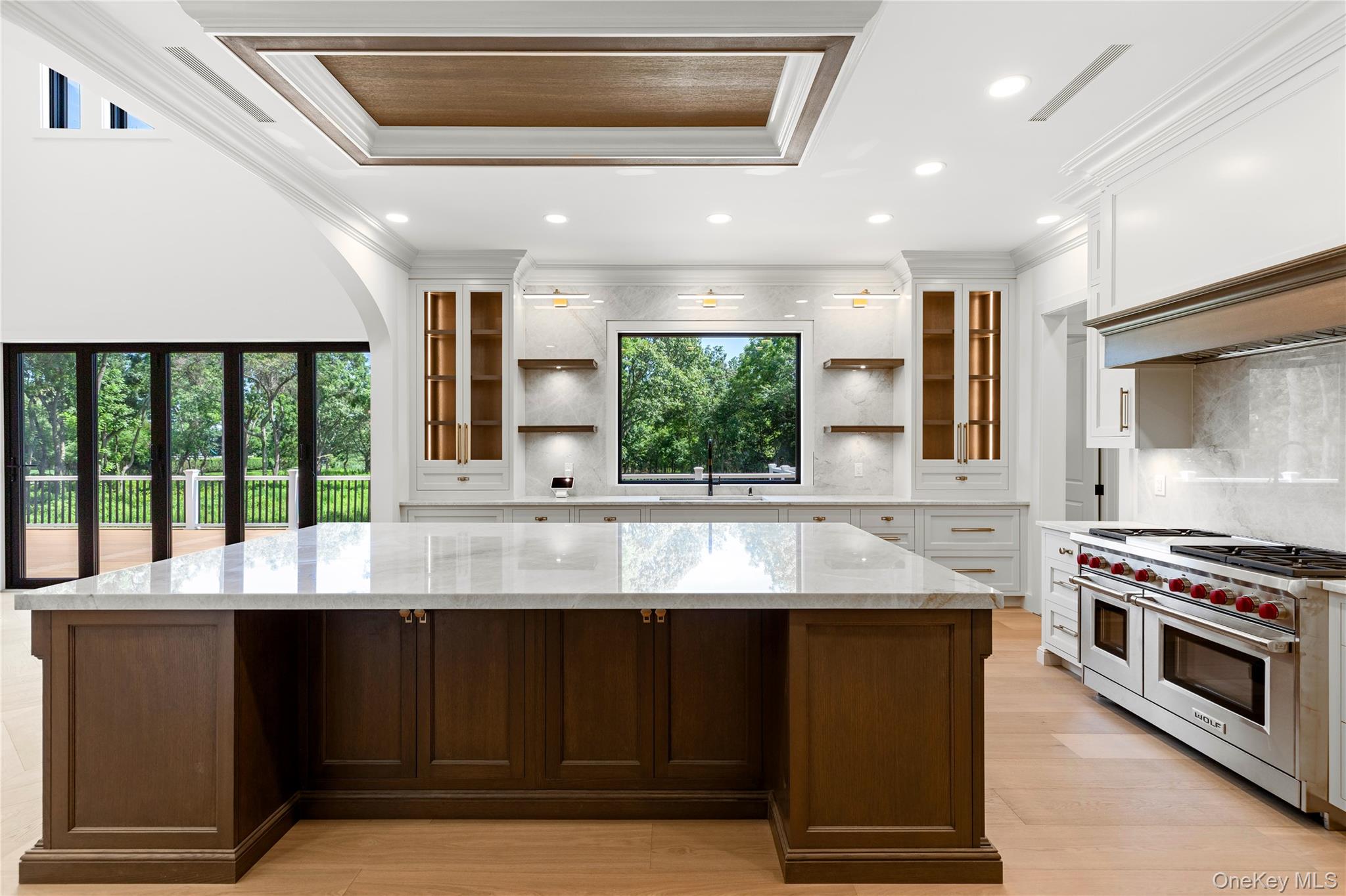 Bright kitchen with a large dark wood island, marble backsplash, and stainless steel range.