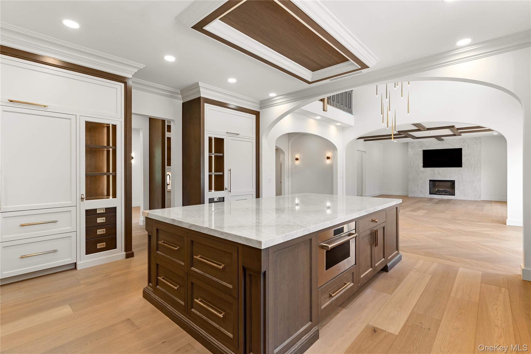 Open-plan kitchen with a marble-topped wood island, built-in cabinetry, and an adjoining living area with fireplace.