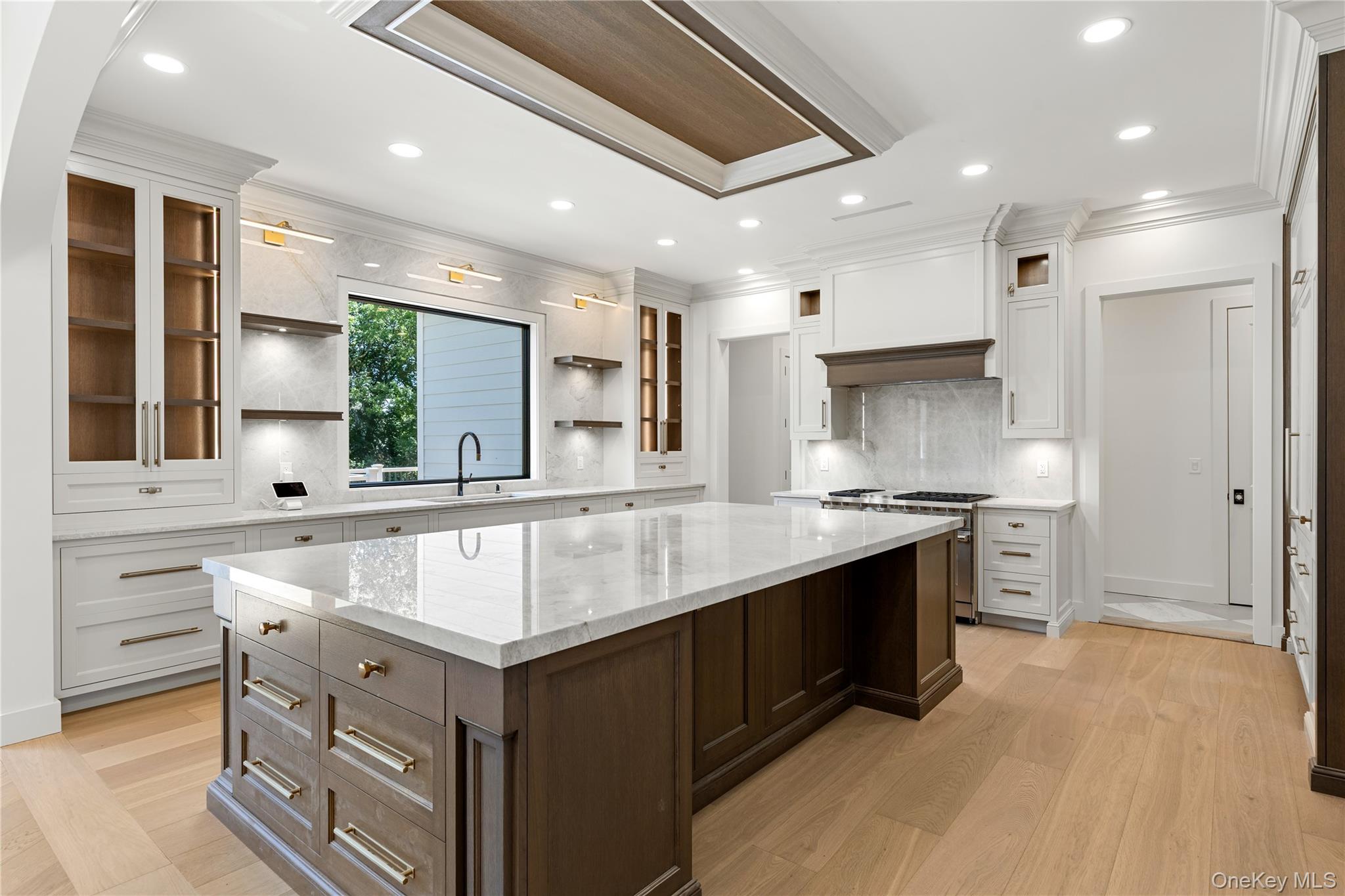Bright kitchen with a large dark wood island, white cabinetry, and a wide window above the sink.