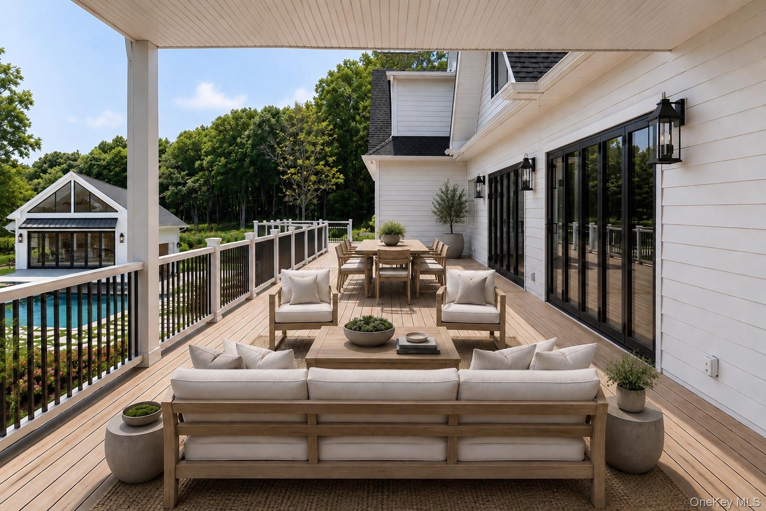 Covered deck with lounge seating and dining table overlooking a swimming pool.