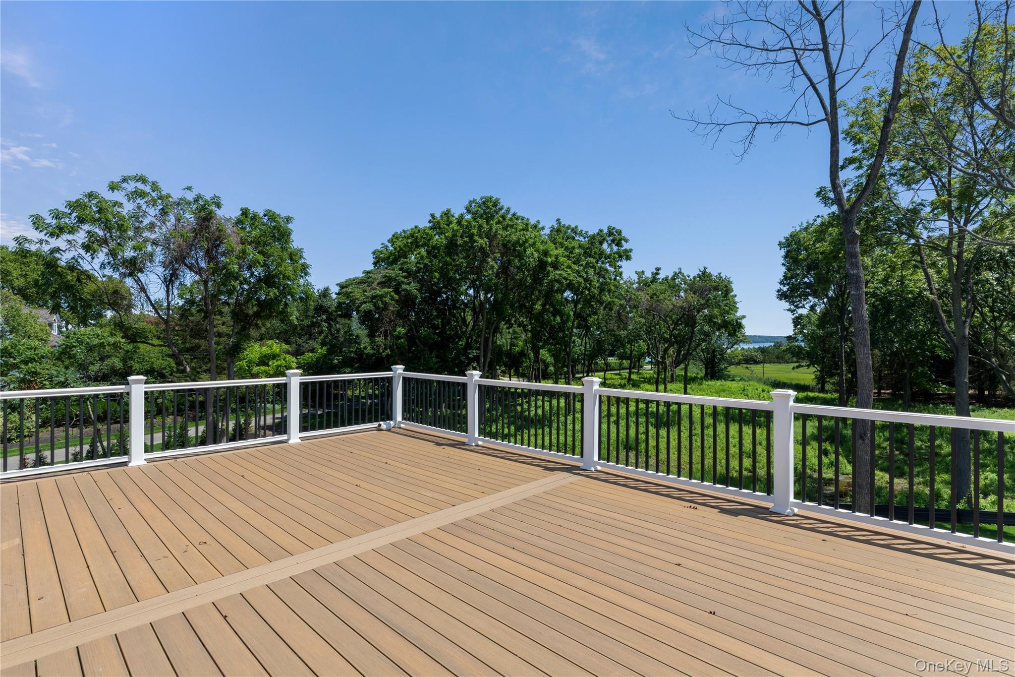 Spacious deck overlooking green grounds and distant water.