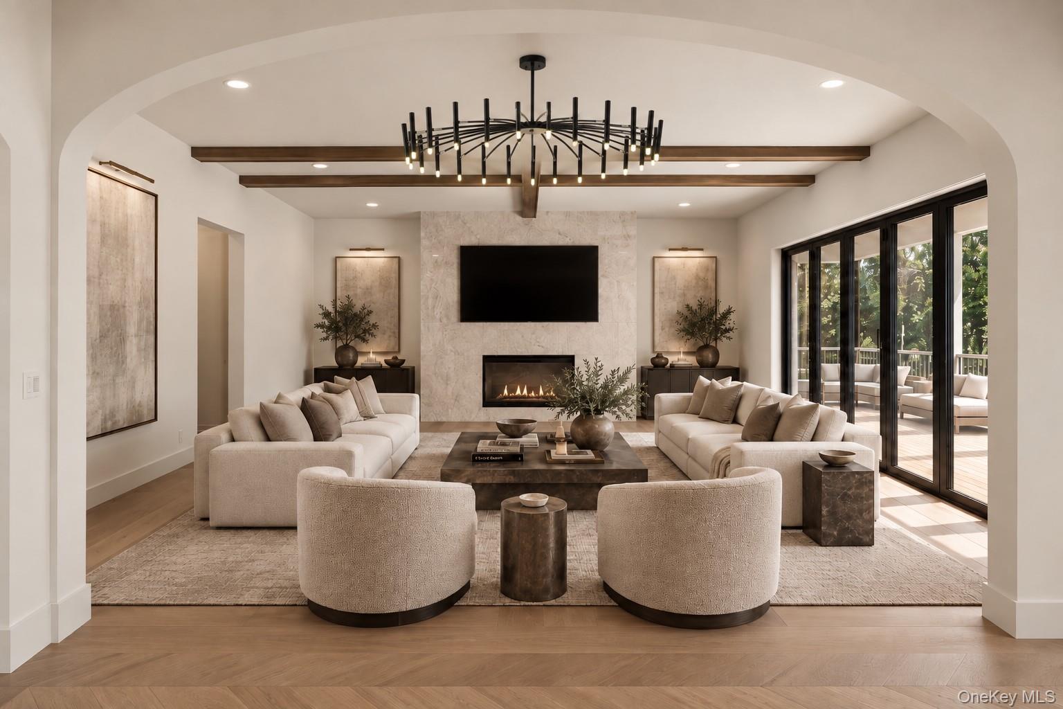Staged living room with a stone fireplace, wood ceiling beams, and large glass doors to a deck.