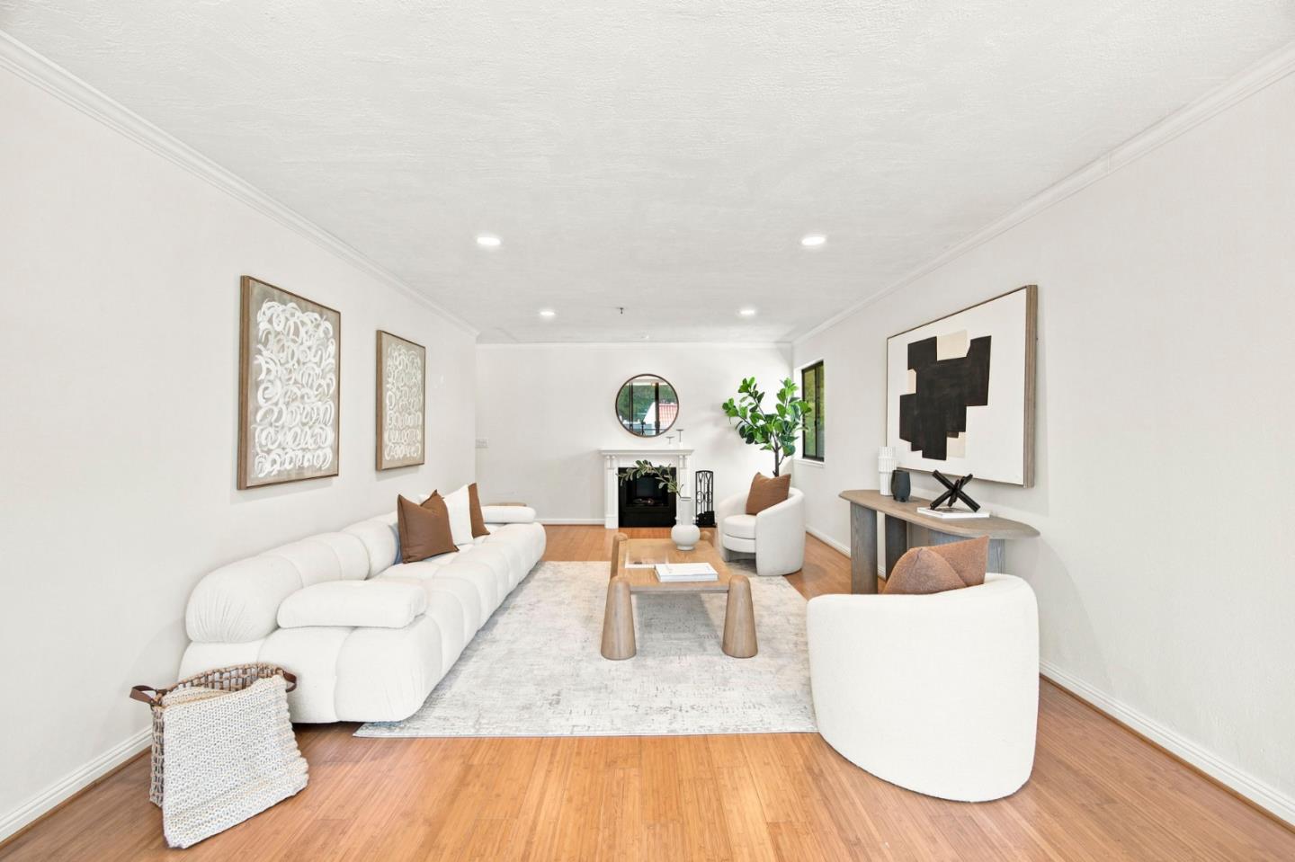 Staged living room with white sofas, warm wood floors, and a fireplace.