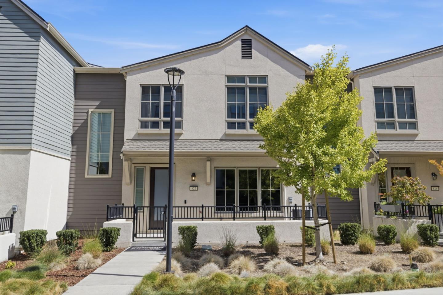 Two-story townhouse with a gated walkway, tall windows, and landscaped front yard.