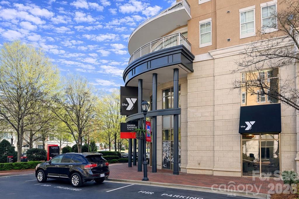 Multi-story building with curved balconies and Harris Express YMCA signs beside a street parking area.