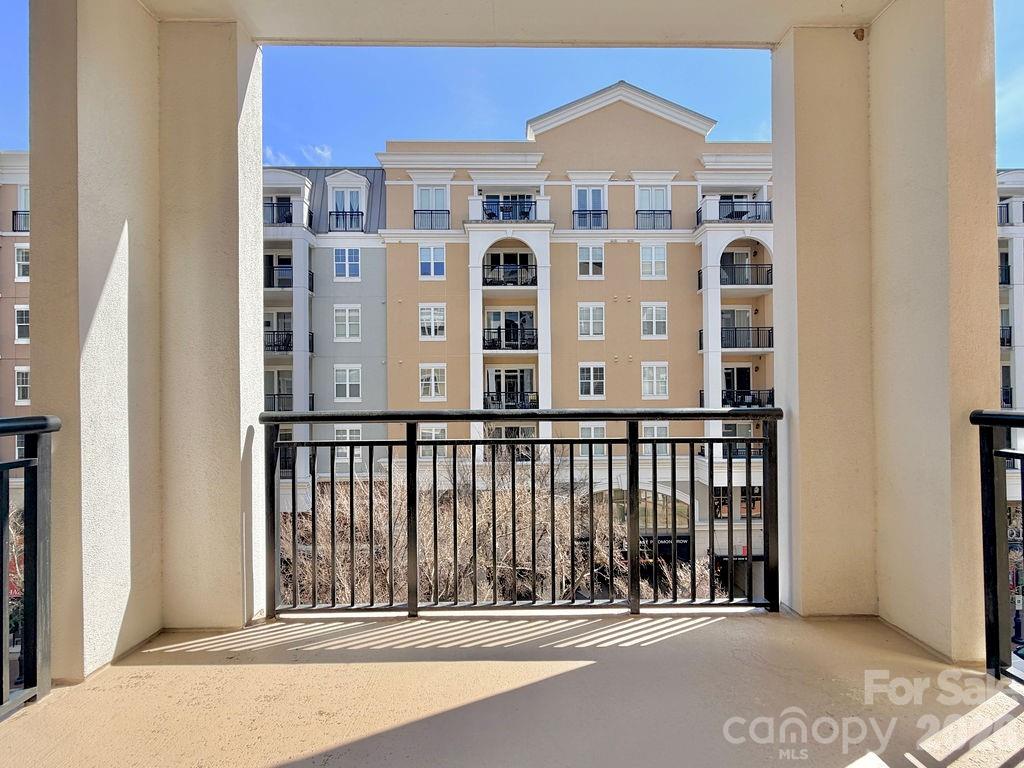 Apartment balcony overlooking a beige and white multi-story building with balconies.