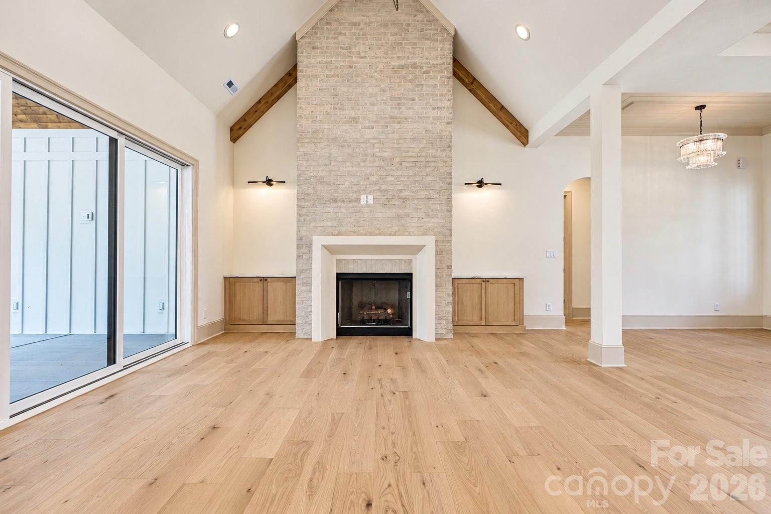 Living room with a tall brick fireplace, vaulted ceiling, and sliding glass doors.