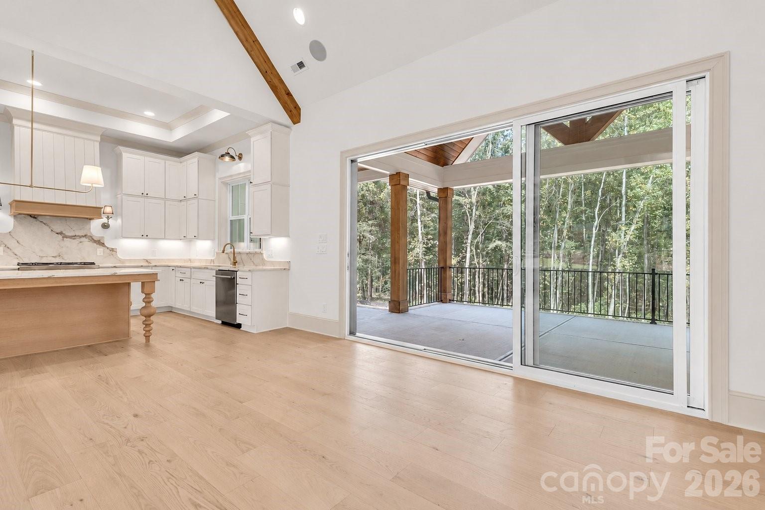 White kitchen opens to a covered, wooded deck through wide sliding glass doors.