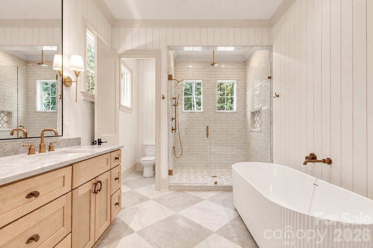 Bathroom with a tiled walk-in shower, freestanding tub, and light wood double vanity.