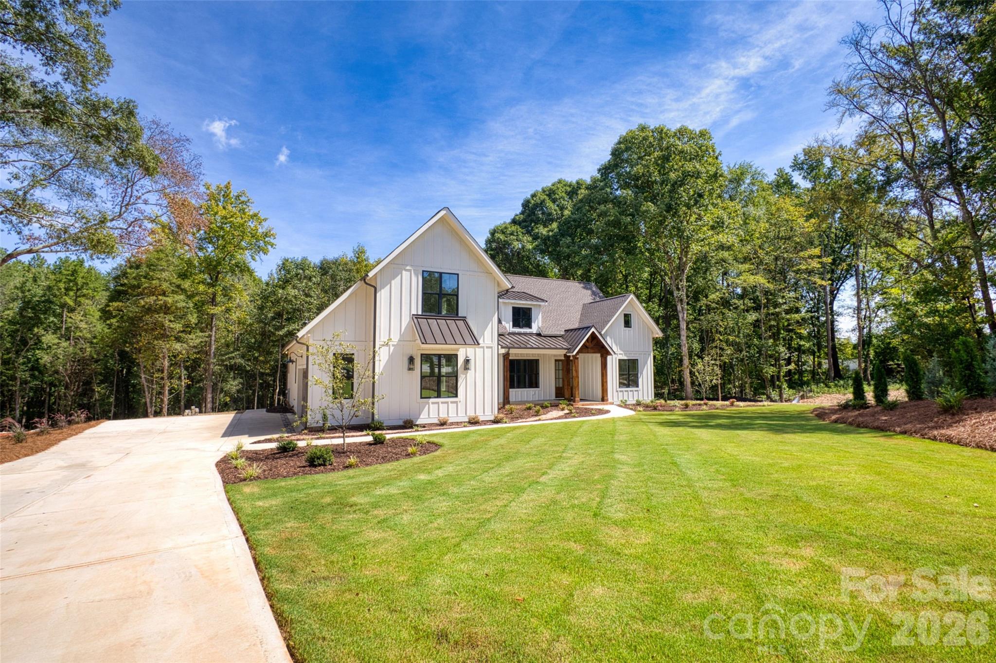 White two-story house with a covered entry, broad lawn, and concrete driveway.